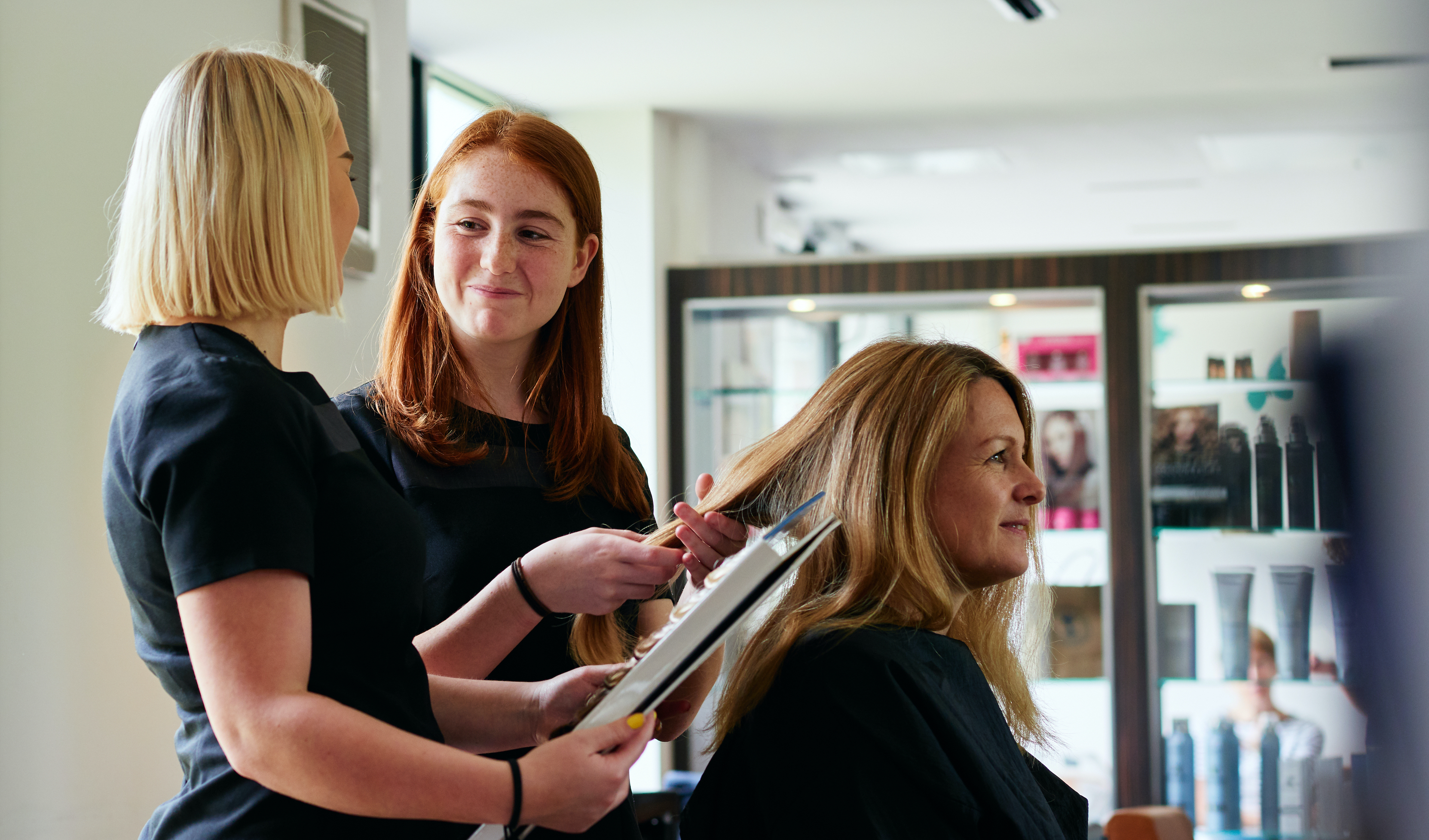 Hair apprentices working with a client in salon
