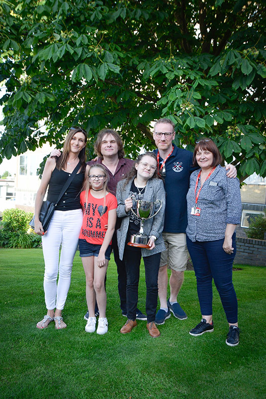 Guitarist Nick McCabe, Jon’s wife and daughter and two music teachers standing next to student who is holding a silver trophy.