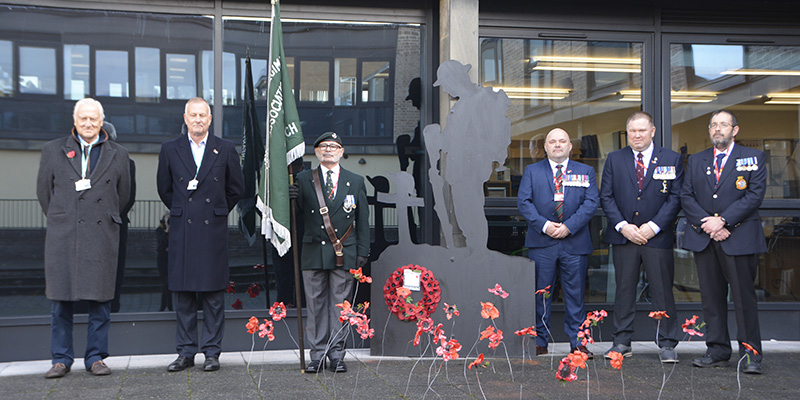 Veterans in uniform in front of poppy display