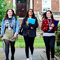three female students walking from college with books 