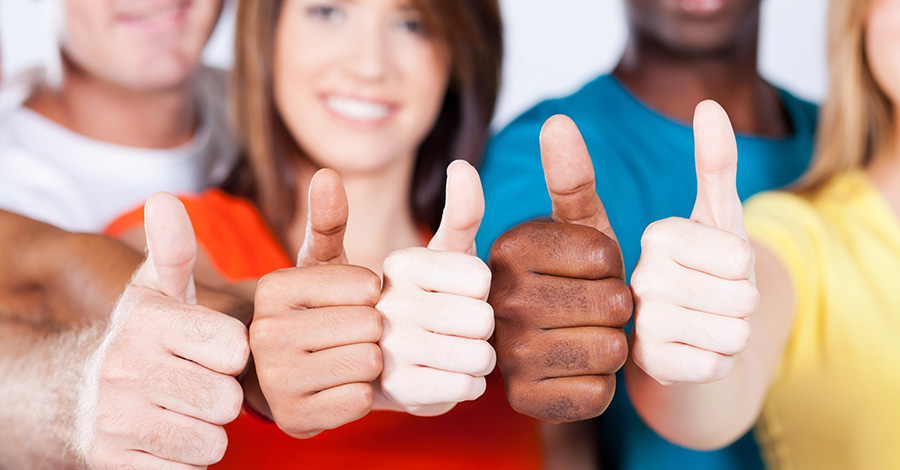 A group of people from diferent ethnic backgrounds with their thumbs up 