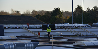 Worker carrying solar panel to be installed on the roof of the Engineering & Construction Centre