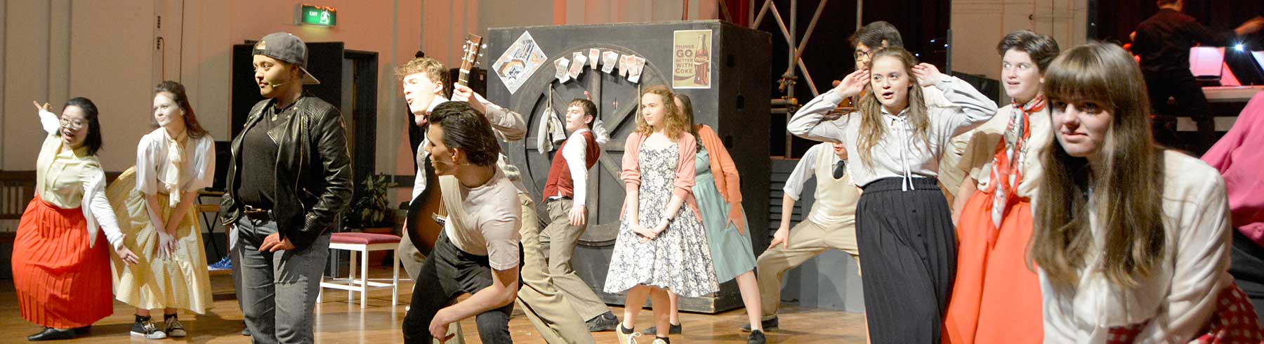 A large group of students rehearsing a play on a stage 