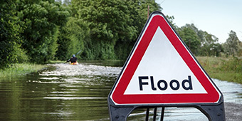Flood sign across flooded road