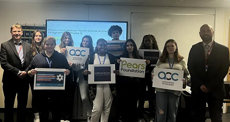 A group of students holding posters next to the college principal
