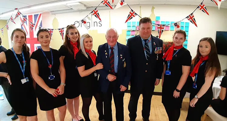 A group of travel and tourism students standing with two veterans