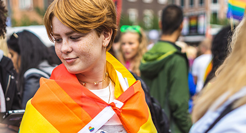 young person with pride flag around their shoulders 