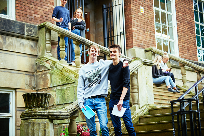 Six A Level students standing and sitting on the steps at English Bridge Campus.