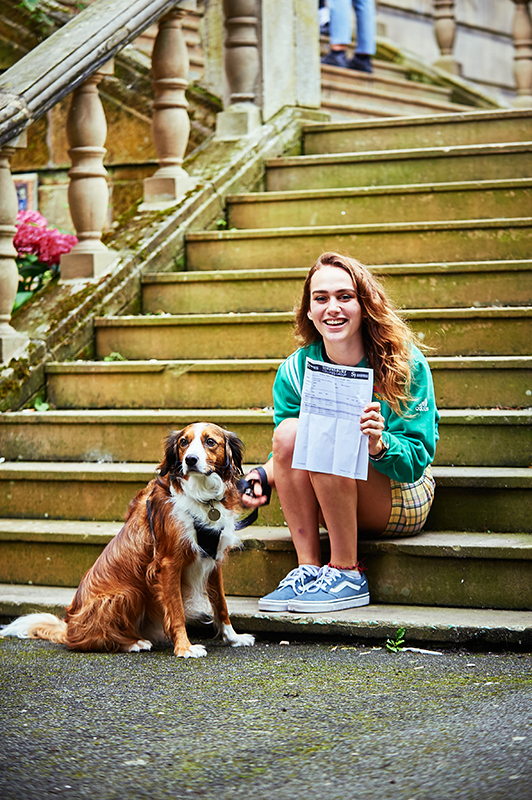 A Level student sitting on the steps at English Bridge Campus with her dog.