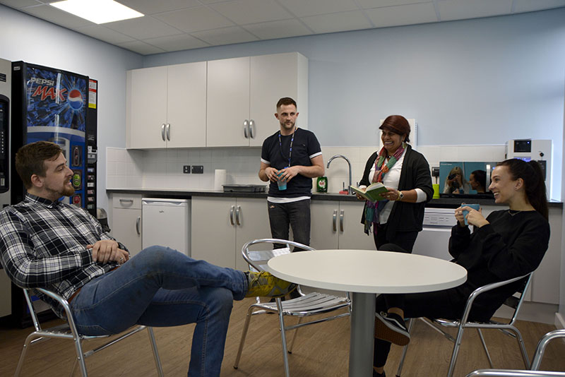 Two male and two female mature students drinking coffee and chatting in the HE Centre’s kitchen.