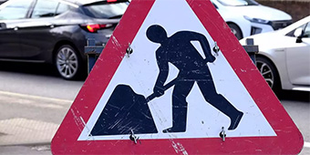 Road work sign in front of cars