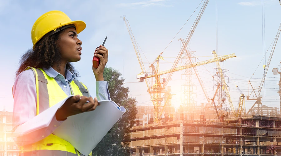 woman on radio in front of construction cranes