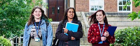Three female students walking in the college groundsteacher talking to male student